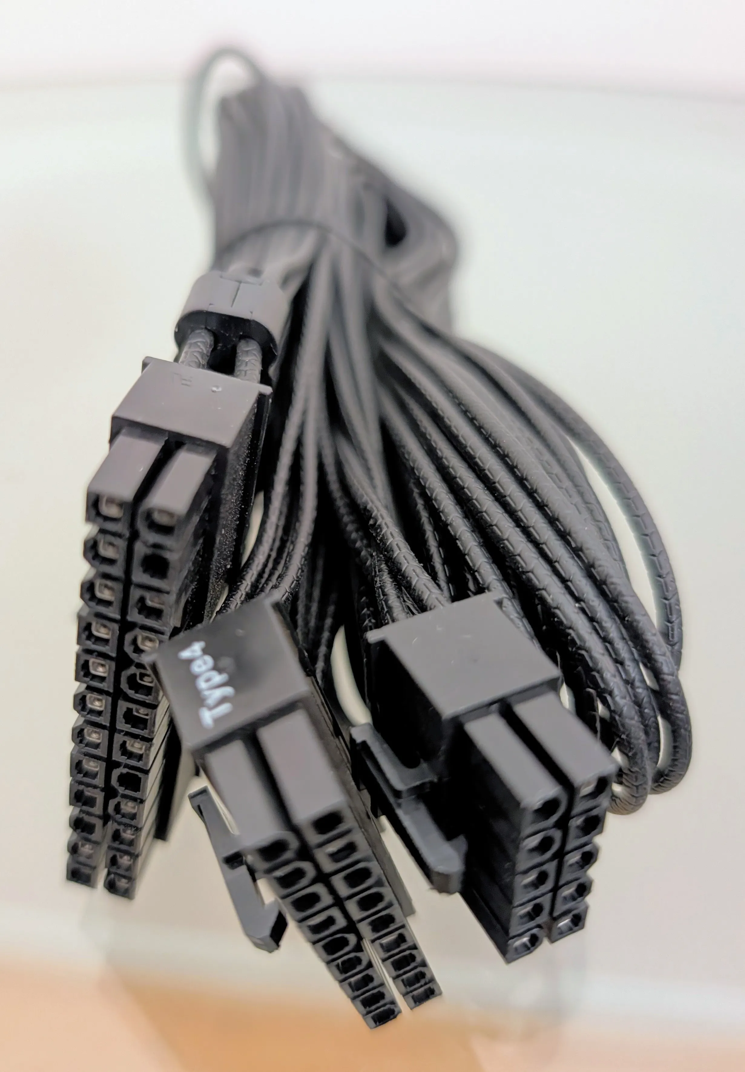 The Corsair 24-pin Type 4 cable showing both ends: the split 10+14 PSU side and the single-block motherboard side that receives the jumper