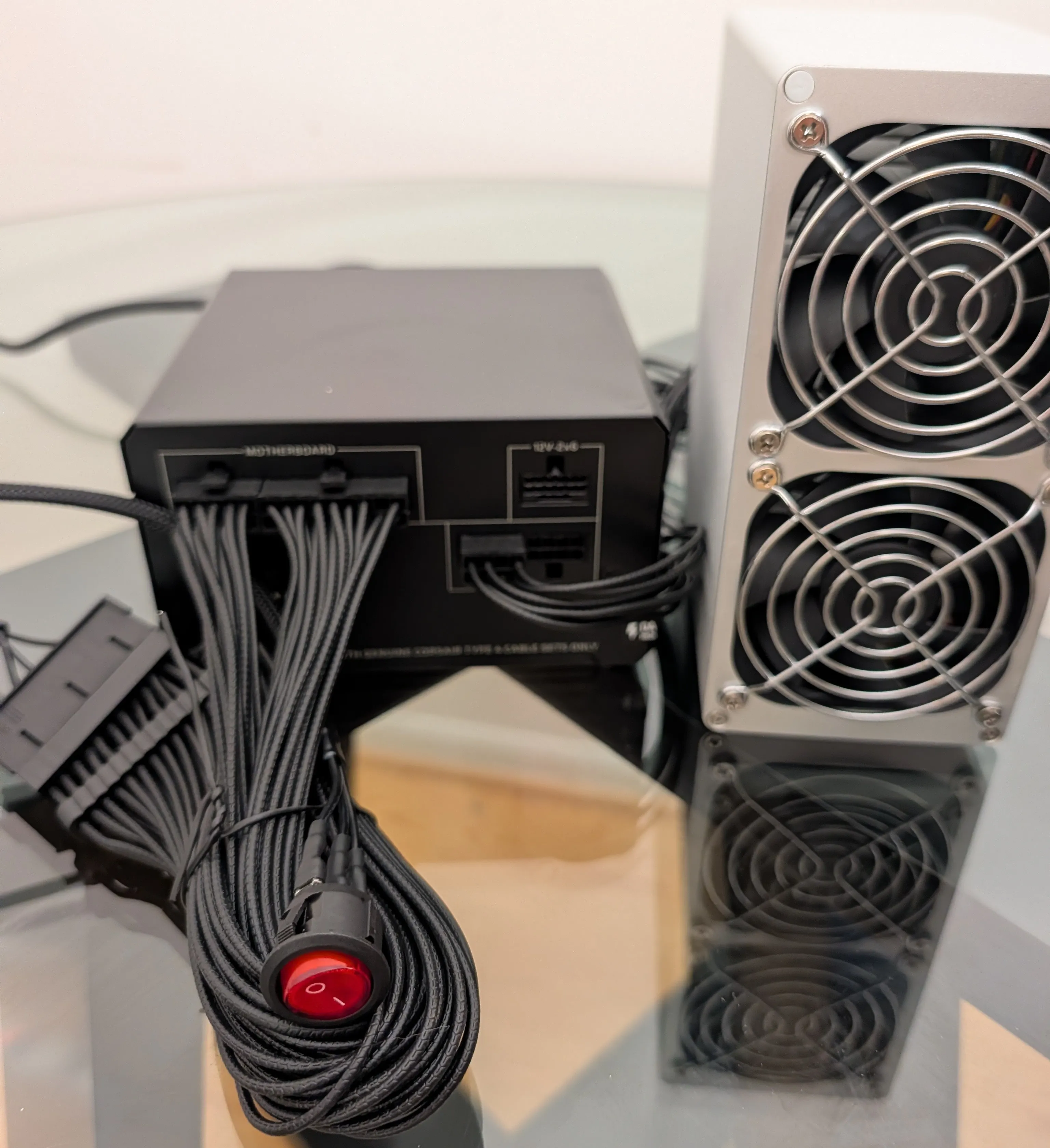 The PSU with the 24-pin cable and jumper attached and the PCIe cable seated, next to the SC Box, before power-on