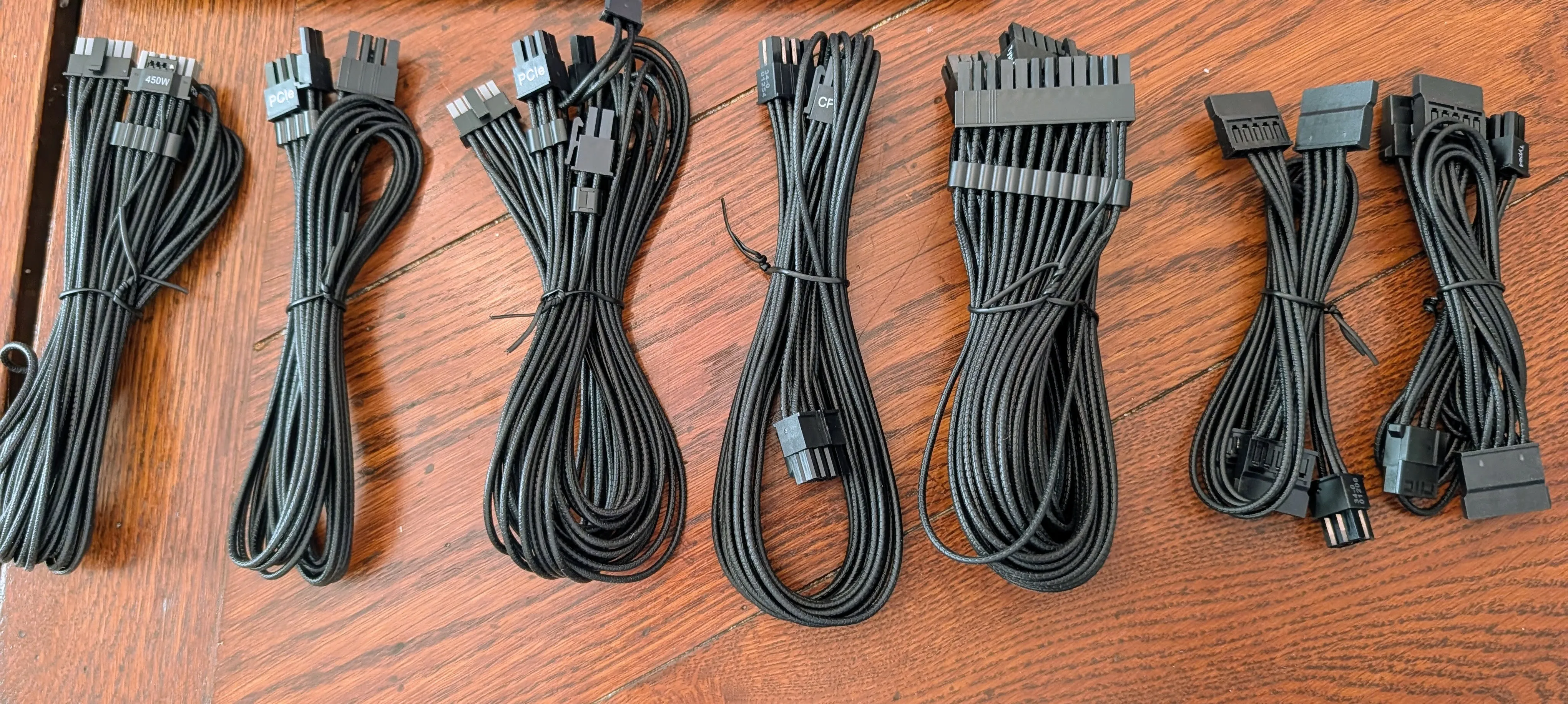 All seven Corsair RM650e cables laid out on the floor, still twist-tied